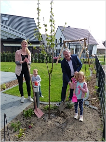 Jacqueline, Felix und Sophie Knufmann freuen sich gemeinsam mit Bürgermeister Martin Tesing über den frisch eingepflanzten Kirschbaum, der hoffentlich schon bald Früchte tragen wird